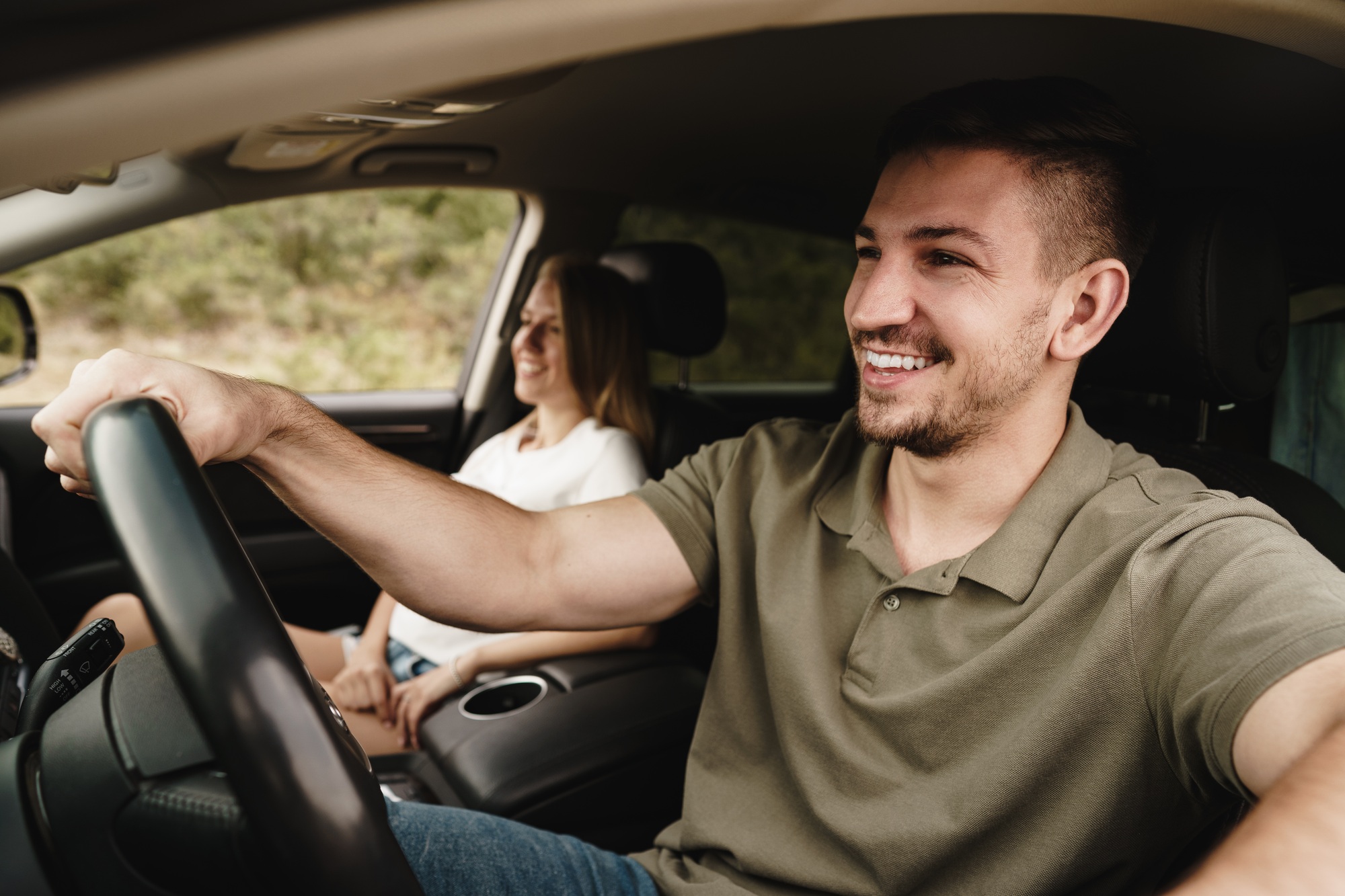 Beautiful young couple sitting on front passenger seats and driving a car