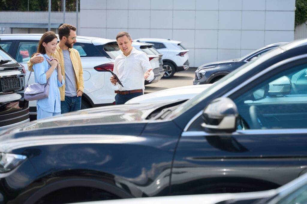 Buyers choose a car in the yard of car dealership