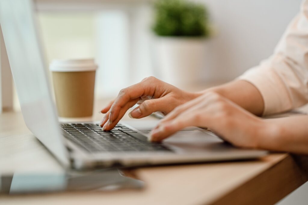 Closeup businesswoman hands typing on laptop searching information or working online.