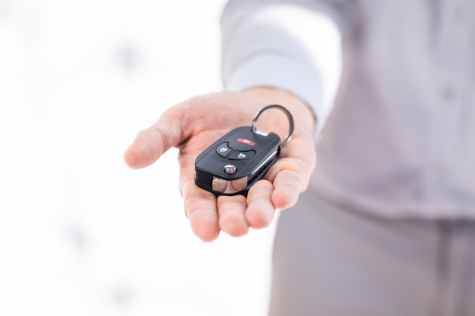 Dealer salesman giving car key to owner. client signing insurance document or rental car lease form